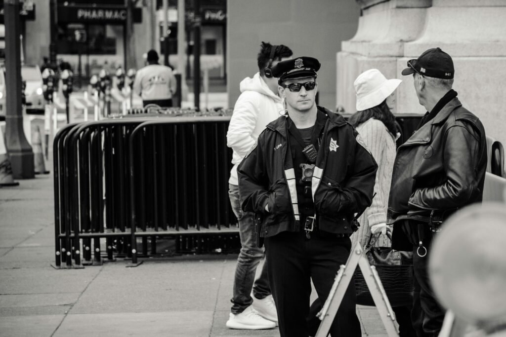 pexels-photo-1119152-1119152 A police officer on patrol in an urban street, engaging in conversation, captured in black and white.